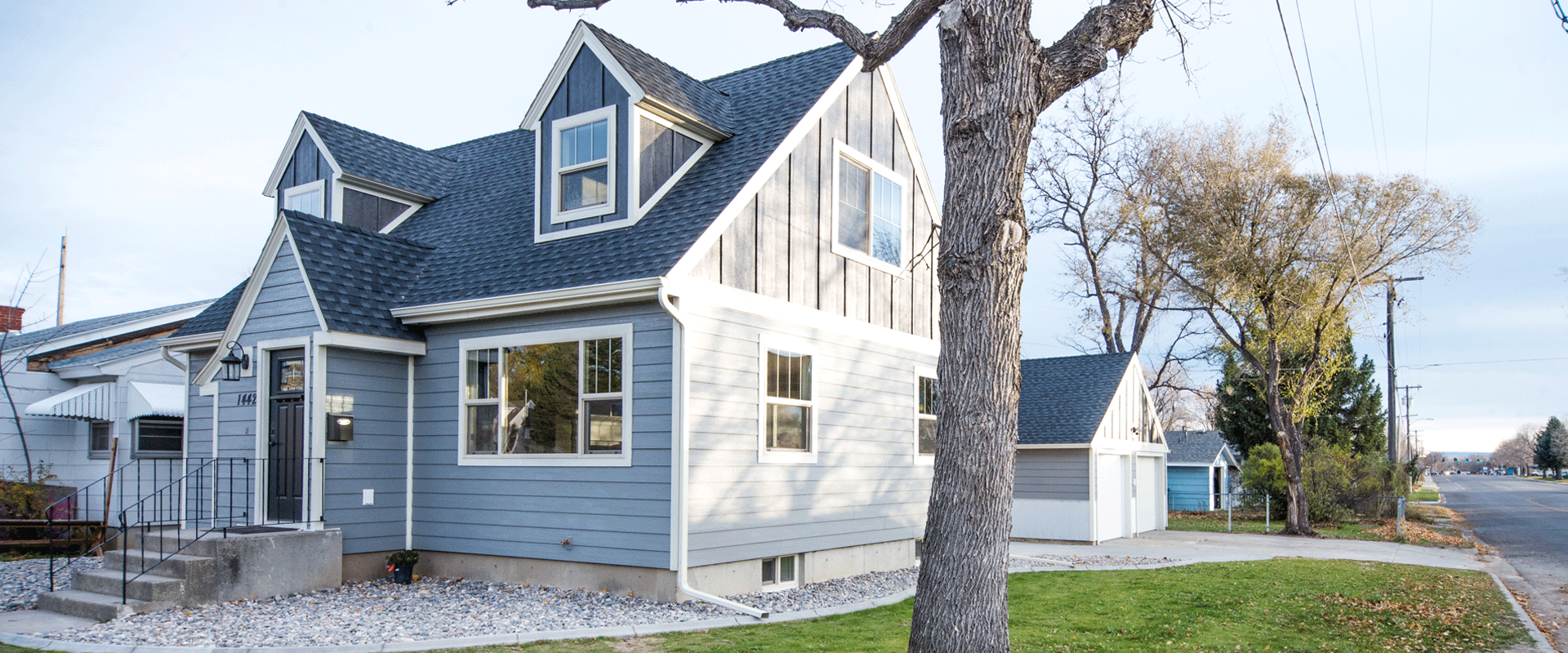 A beautiful light blue home with darker, blue attic accent, and white trim.